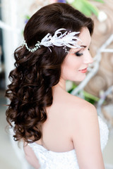 Portrait of the bride. A white brunch of flowers in a beautiful bride's dark curly hair
