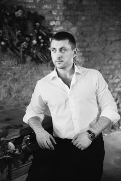 A young man in a white shirt builds on a chest of drawers and looking confident, black and white picture