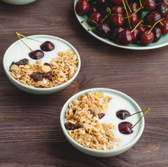 Healthy breakfast with muesli, yogurt and ripe cherries on a wooden rustic table
