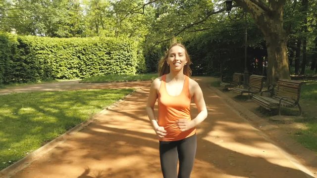Jogging woman running in city park in sunshine on beautiful summer day.