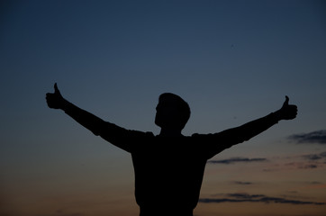 silhouette of man standing in a field at sunset.