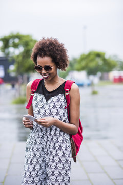 Portrait of smiling young woman looking at her smartphone