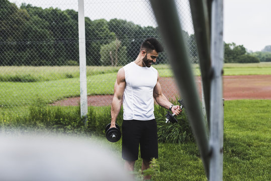 Athlete exercising with dumbbells on sports field