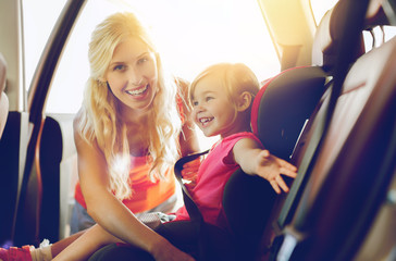 happy mother fastening child with car seat belt