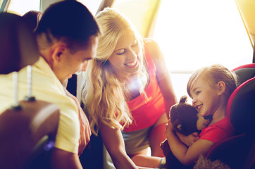 happy parents with little girl in baby car seat