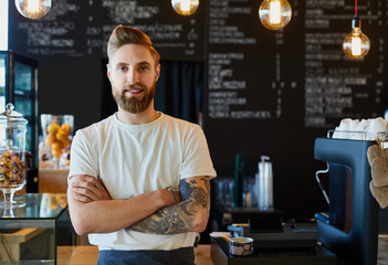 Happy barista standing at trendy coffee shop, cafe - small busin
