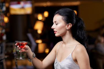 glamorous woman with cocktail at night club or bar