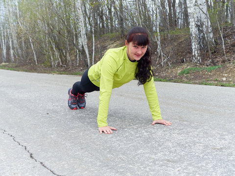  Young woman pushups outdoors in nature.