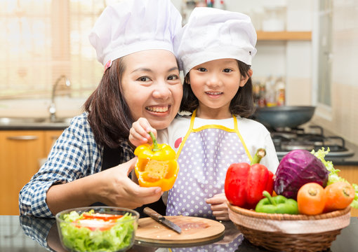 Asian mother teaching daughter making salad in kitchen,Cooking  concept of happy asian little girl and mother making salad 