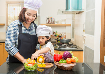 Asian mother teaching daughter making salad in kitchen,Cooking  concept of happy asian little girl and mother making salad 