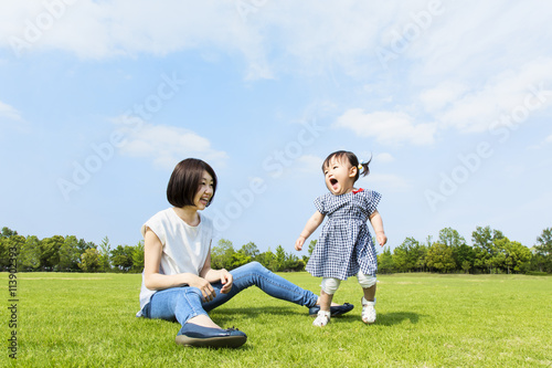 青空の下 芝生の公園で幼い女の子と遊ぶお母さん Wall Mural Qiteng T