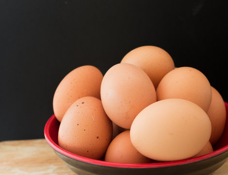 An eggs in a bowl on wooden board and black background
