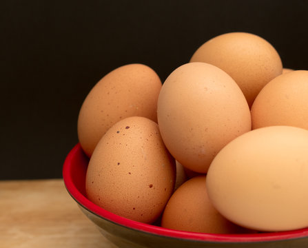 An eggs in a bowl on wooden board and black background