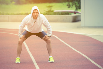 Obraz premium Young athlete preparing for the morning workout on the running track. Urban scene. Sport, workout, healthy lifestyle, fitness concepts. 