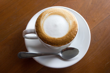 Cup of cappuccino art coffee with froth milk and wooden backgrou