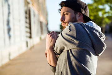 Fototapeta premium Young man stretching after running in the street.