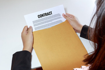 Woman hands holding contract document in envelope