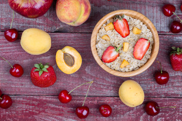 Oatmeal porridge with apricots, cherry, apple and strawberry on
