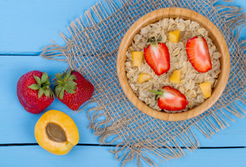 Oatmeal porridge with apricots and strawberry on table