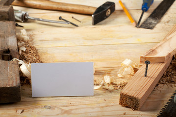 Business card on wooden table for carpenter tools with sawdust.