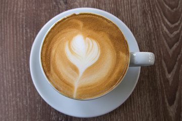 Cup of latte art coffee with froth shape heart and wooden backgr