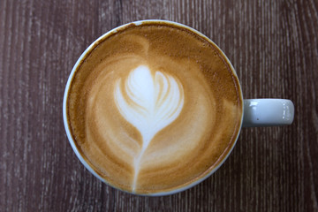 Cup of latte art coffee with froth shape heart and wooden backgr