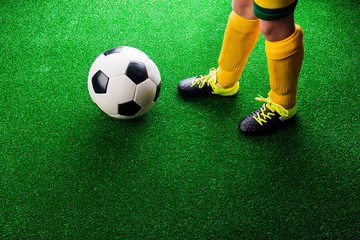 Obraz premium Unrecognizable little football player against green grass, studi