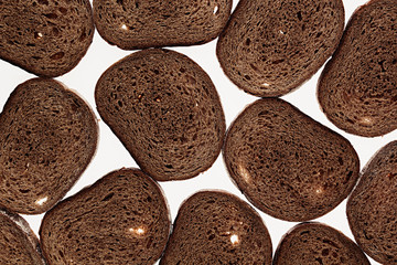 Slices of black rye bread on a white background. Food background. Pattern.