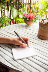 Female hand writing in a notebook on wooden table