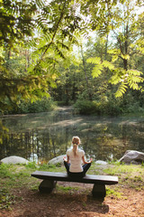 Girl doing yoga in forest lake