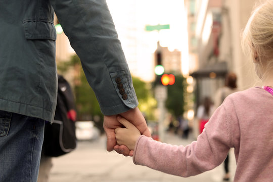 father holding  the daughter/child  hand  behind  the traffic lights