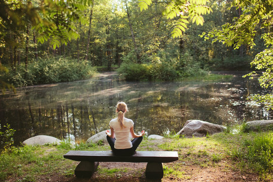 Girl doing yoga in forest lake