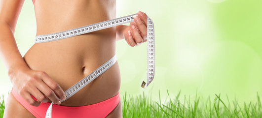 A slim girl measuring her waist.