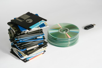 Pile of floppy disks, cd-roms, external hard drive and pen over white