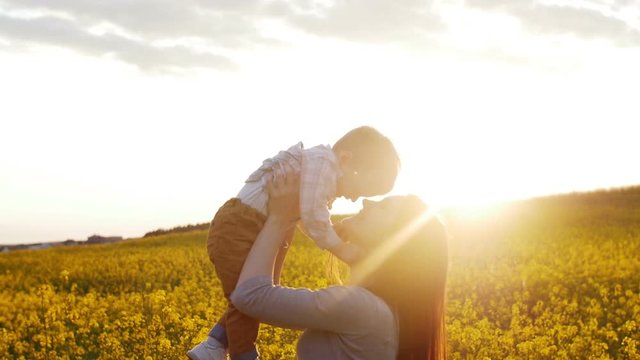 mother plays with son at field at sunset. Slow mo