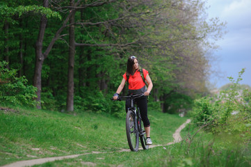 Naklejka premium Girl riding a bike in the woods
