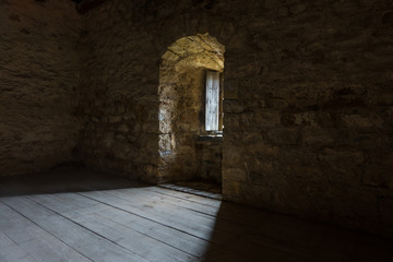 .Dark room with stone walls and window .