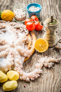 Whole raw octopus with lemon and vegetables on cutting board