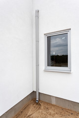 New rain gutter on a white wall with window