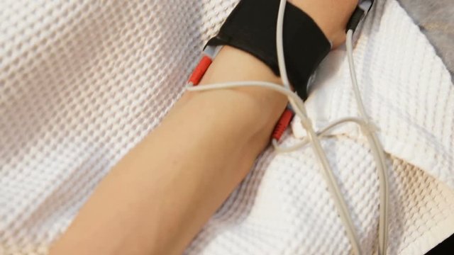 Woman receiving an electro therapy at the health center.Attractive female patient receiving electro threrapy beauty treatment.An attractive girl with electrodes on his hands received electrical