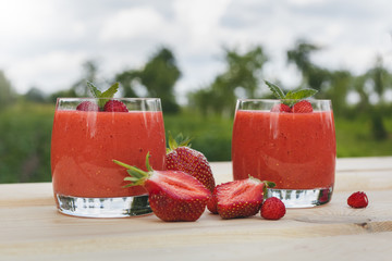 glass of strawberry smoothie on wooden table with mint