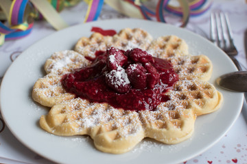 homemade heart waffle on a white plate with fresh made raspberry compote