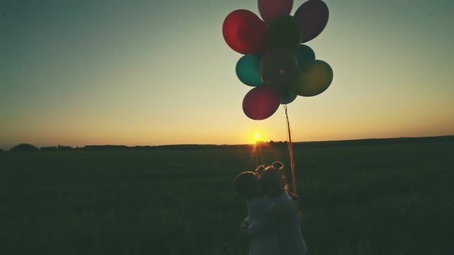 The boy with the girl embrace on a background of a sunset holding balloons in hands. RAW video record.