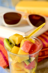 fruit salad, sunglasses, book and beach towel