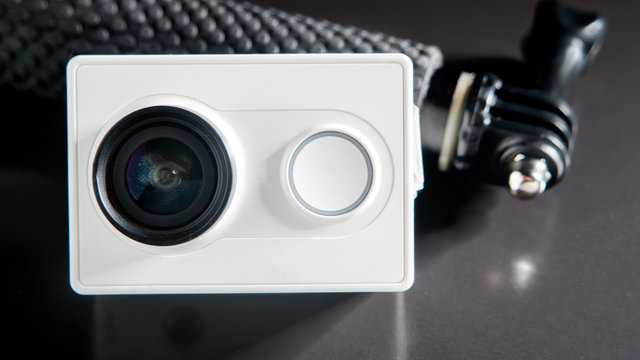 Action camera and small monopod head on black background, selective focus - Powered by Adobe