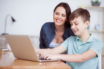 Happy mother helping his son to do homework