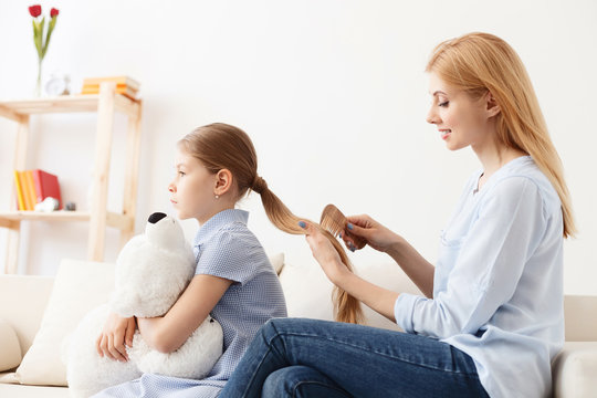 Mother combing hair of daughter