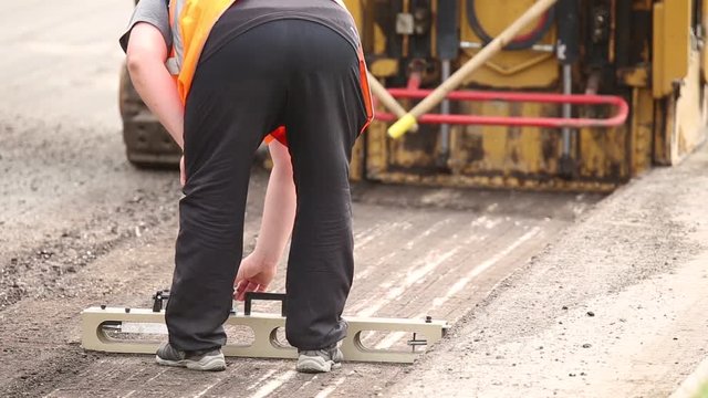 Repair of asphalt roads, machine for removing asphalt pavement roads, the worker makes measurements
