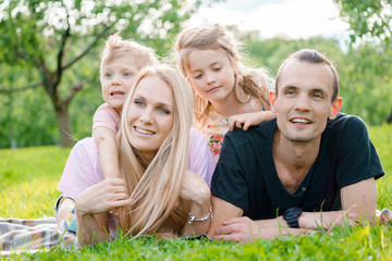 Fototapeta premium Młoda rodzina leżąc na trawie w okolicy