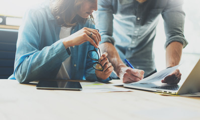 Fototapeta premium Coworking team brainstorming process in modern office.Project manager analyze reports,holding glasses female hand.Young business crew working with startup studio.Laptop wood table.Blurred,film effec